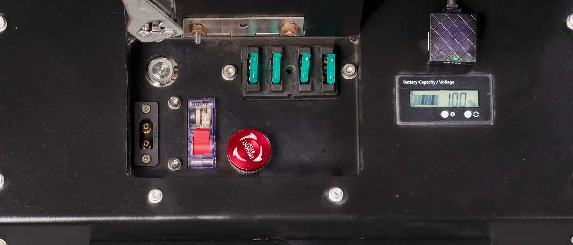 The vehicle control panel: the red emergency stop beside the battery isolator, the fuse bank and a charge gauge.